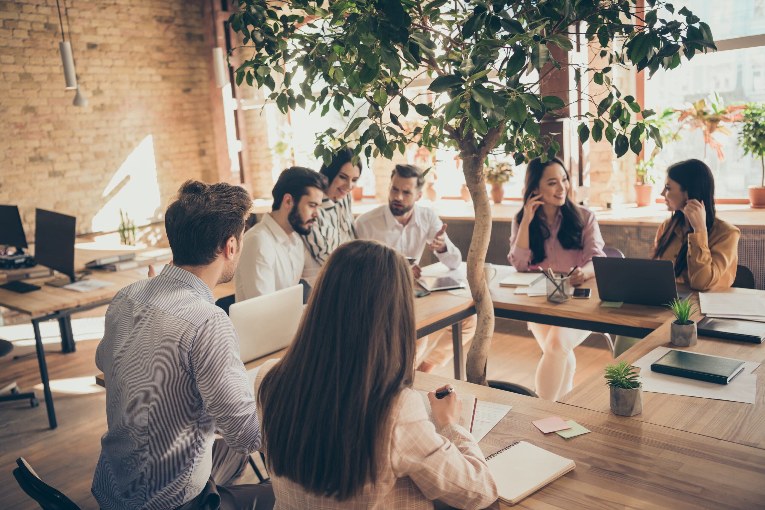 Menschen sitzen gemeinsam an einem Tisch in einem modernen B&uuml;ro und arbeiten im Team..