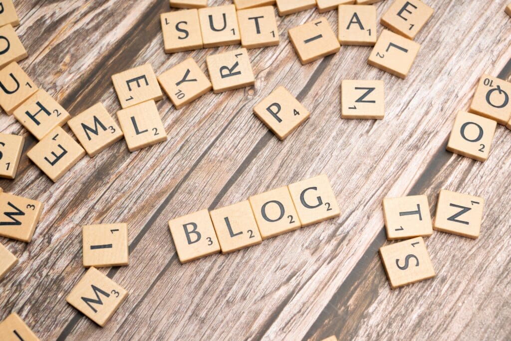Scrabble-Buchstaben liegen auf einem Holztisch; in der Mitte steht das Wort &sbquo;Blog&lsquo;.